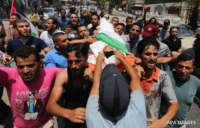 Mourners carry the body of Palestinian Louay Kahil, who was killed in an Israeli air strike, during his funeral in Gaza city on July 15, 2018. Photo by Ashraf Amra