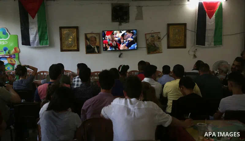 Palestinians watch on a screen the Russia 2018 World Cup final football match between France and Croatia, in the West Bank city of Nablus on July 15, 2018. Photo by Shadi Jarar'ah