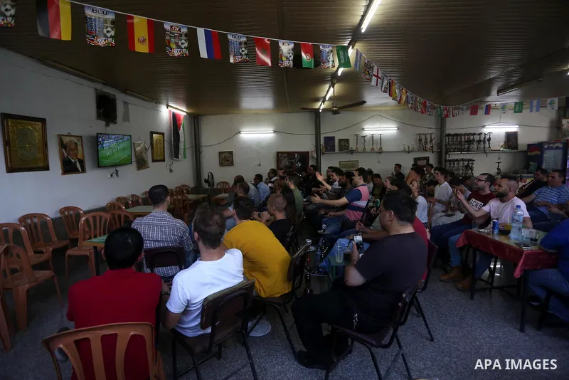 Palestinians watch on a screen the Russia 2018 World Cup final football match between France and Croatia, in the West Bank city of Nablus on July 15, 2018. Photo by Shadi Jarar'ah