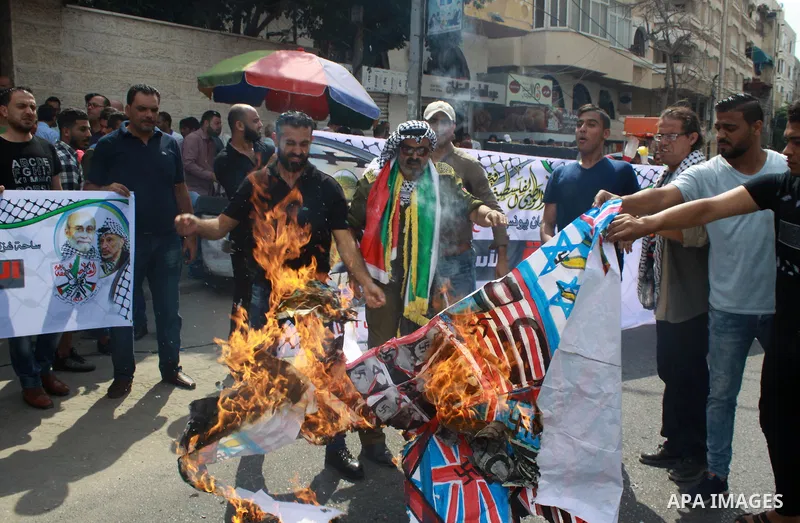 Palestinians burn an Israeli, British and U.S. flags during a protest to show solidarity with Palestinian prisoners held in Israeli jails, in front of Red cross office in Gaza city on July 16, 2018. Photo by Bashar Zakri