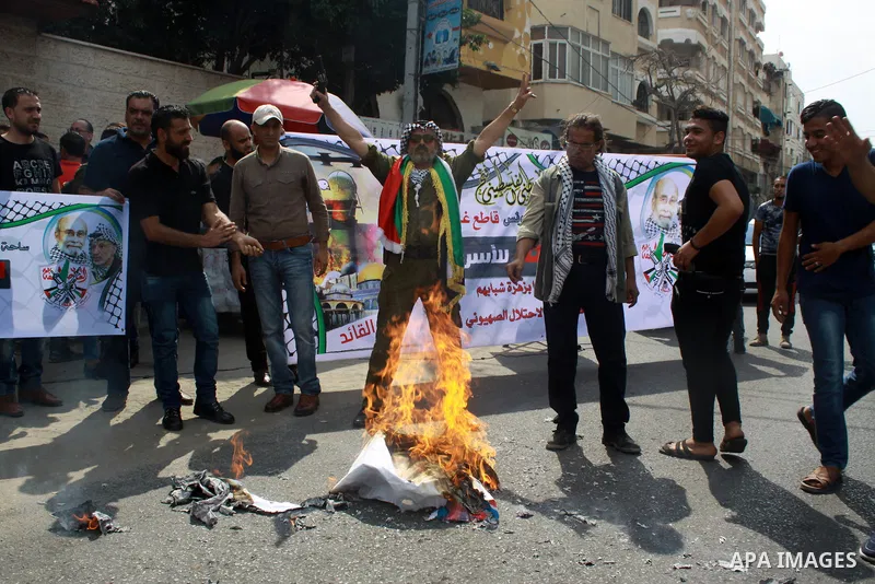 Palestinians burn an Israeli, British and U.S. flags during a protest to show solidarity with Palestinian prisoners held in Israeli jails, in front of Red cross office in Gaza city on July 16, 2018. Photo by Bashar Zakri