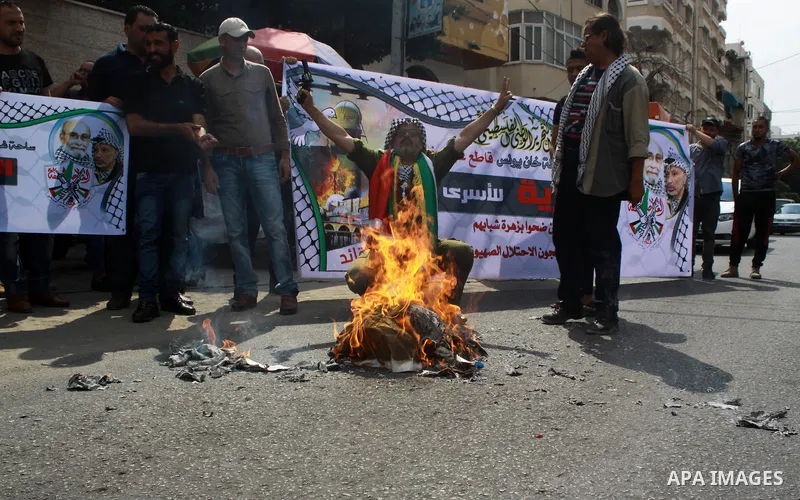 Palestinians burn an Israeli, British and U.S. flags during a protest to show solidarity with Palestinian prisoners held in Israeli jails, in front of Red cross office in Gaza city on July 16, 2018. Photo by Bashar Zakri