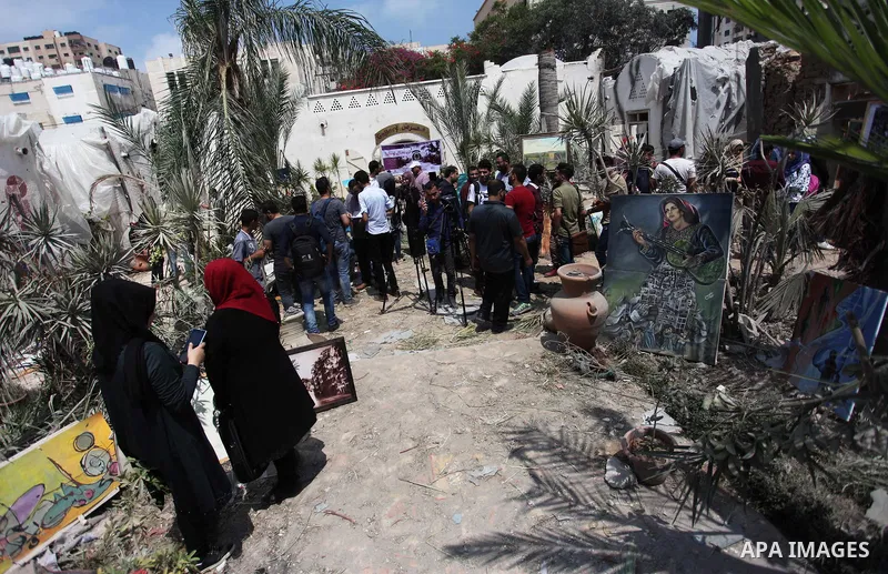 Palestinian artists take part in an exhibition against the bombing of the Arts and Crafts Village that was damaged in an Israeli airstrike on the Gaza City, on July 16, 2018. Photo by Mahmoud Ajour