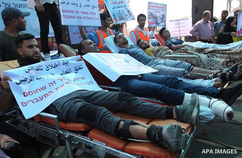 Palestinians who were wounded by Israeli troops during clashes at Israeli-Gaza border, take part in a protest to demand their rights to travel for treatment and against the siege on the Gaza Strip, at Erez crossing, in t...