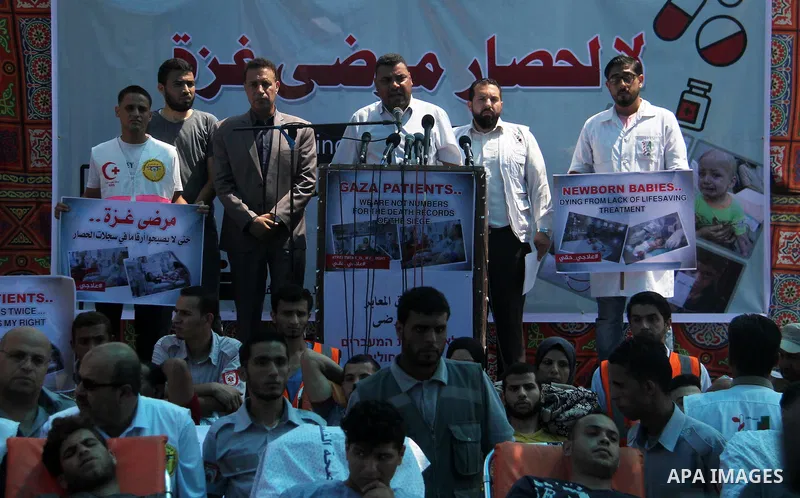 Ashraf al-Qudra, a spokesman for the health ministry in Gaza strip, speaks a press conference, while Palestinians who were wounded by Israeli troops during clashes at Israeli-Gaza border, take part in a protest to demand...