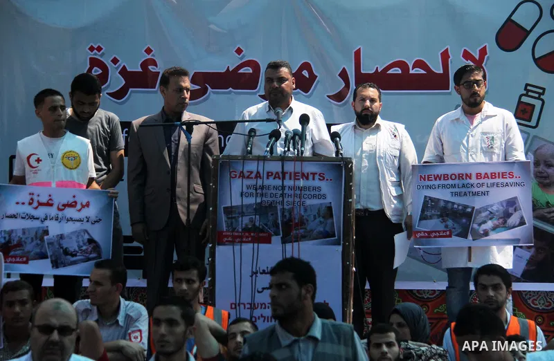 Ashraf al-Qudra, a spokesman for the health ministry in Gaza strip, speaks a press conference, while Palestinians who were wounded by Israeli troops during clashes at Israeli-Gaza border, take part in a protest to demand...