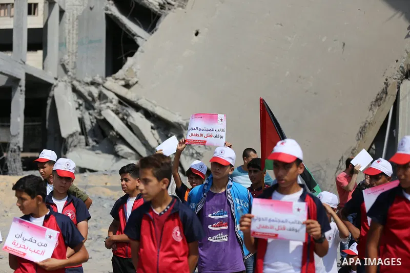 Palestinian boys take part in a protest against the killing of Palestinian children, in front of the building that was damaged in an Israeli airstrike on the Gaza City, on July 17, 2018. Photo by Ashraf Amra