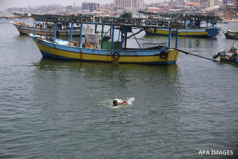 A Palestinian man swims at the seaport of Gaza City on July 17, 2018, while the fishing zone enforced by Israel off the Gaza Strip was also reduced from six nautical miles to three. Israel tightened its blockade of the G...