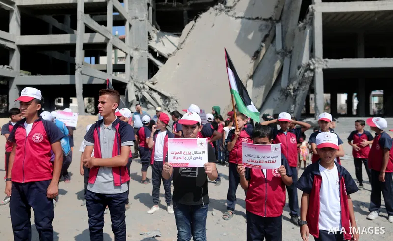 Palestinian boys take part in a protest against the killing of Palestinian children, in front of the building that was damaged in an Israeli airstrike on the Gaza City, on July 17, 2018. Photo by Ashraf Amra