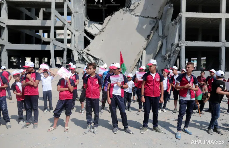 Palestinian boys take part in a protest against the killing of Palestinian children, in front of the building that was damaged in an Israeli airstrike on the Gaza City, on July 17, 2018. Photo by Ashraf Amra