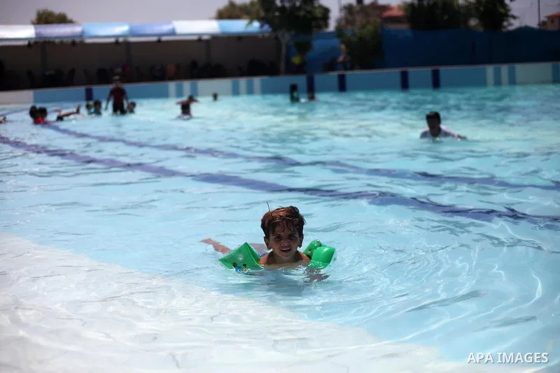 Palestinian children swim in a pool at an amusement park during the summer holiday, in Gaza city on July 19, 2018. Photo by Mahmoud Ajour