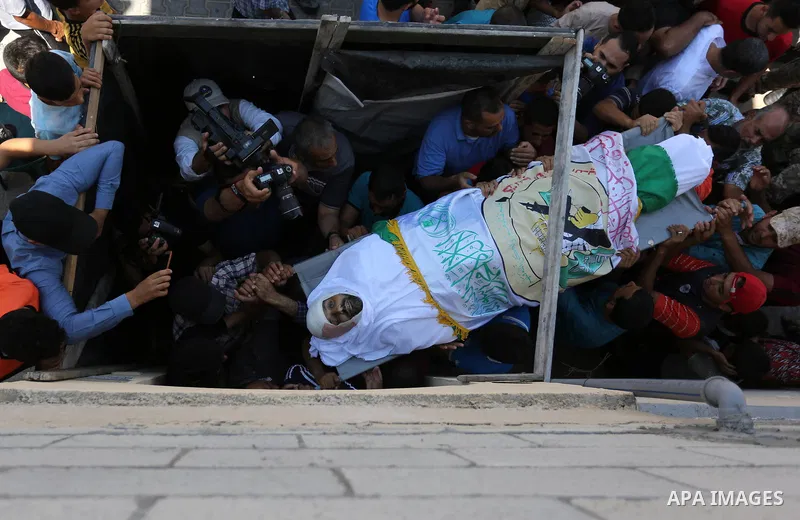 Mourners carry the body of Palestinian Abdul Karim Radwan, who was killed in an Israeli air strike, during his funeral in Rafah in the southern of Gaza Strip July 20, 2018. Photo by Ashraf Amra