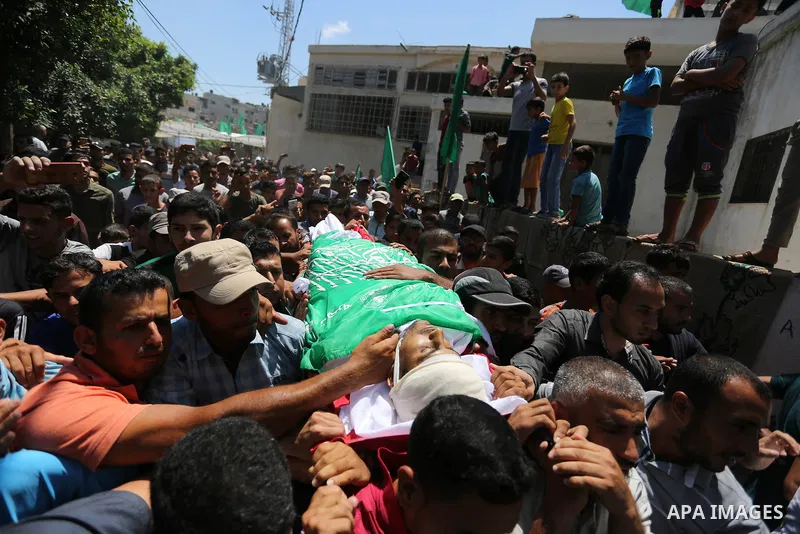 Mourners carry the body of Palestinian militant Mohammed Abu Dakah, 31, who was killed in an Israeli strike, during his funeral in Khan Younis in the southern of Gaza Strip, on July 21, 2018. Photo by Ashraf Amra