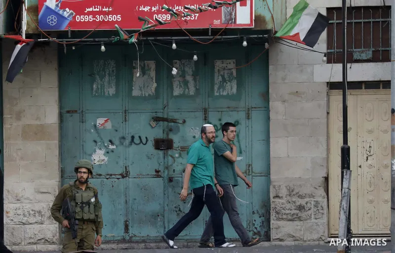 Israeli settlers walk towards the tomb of Atnaeil Ben Kinaz, a Jewish religious site in the divided West Bank town of Hebron on July 22, 2018. Photo by Wisam Hashlamoun