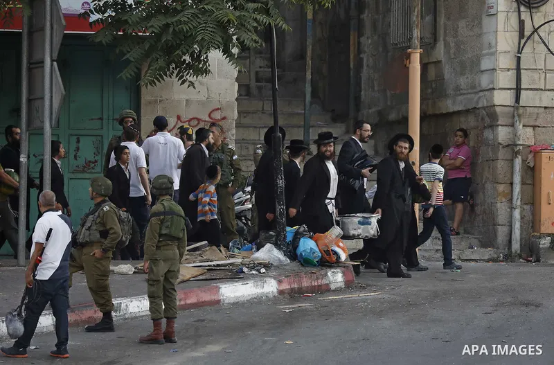 Israeli settlers walk towards the tomb of Atnaeil Ben Kinaz, a Jewish religious site in the divided West Bank town of Hebron on July 22, 2018. Photo by Wisam Hashlamoun