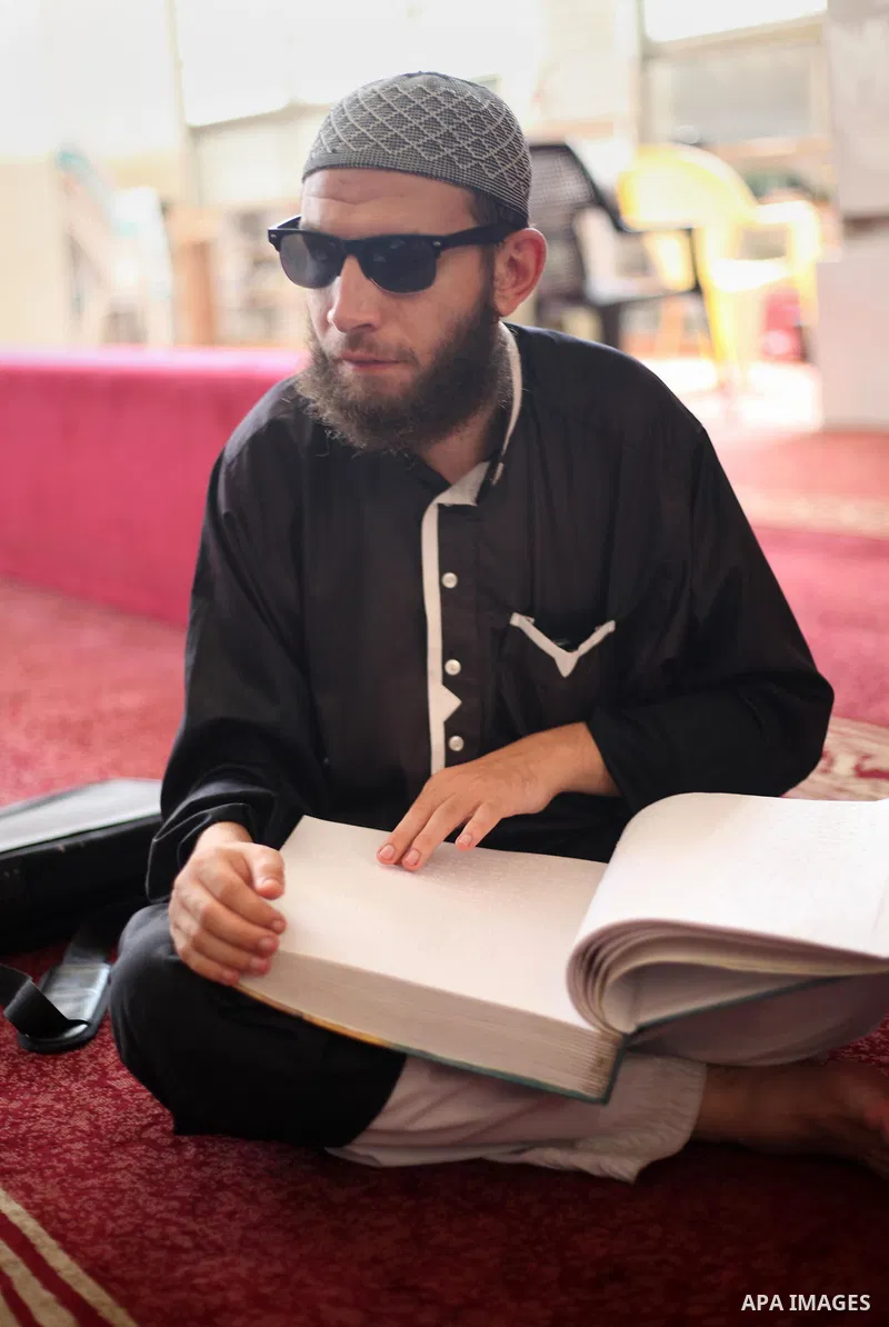 A Palestinian blind boy reads and memorise the holy Quran in braille at Dar al-Quran and Sunnah in Gaza city, on July 23, 2018. Photo by Mahmoud Ajour