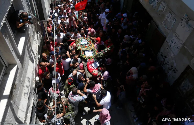 Mourners carry the body of Palestinian teenager Arkan Mezeher, who was killed by Israeli soldiers during a raid, during his funeral in Dheishe refugee camp, near West Bank city of Bethlehem on July 23, 2018. Photo by Wis...