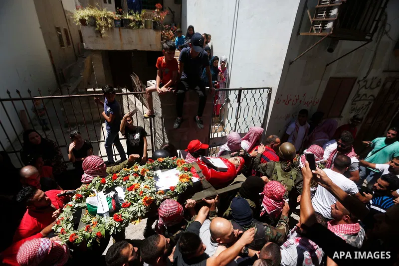 Mourners carry the body of Palestinian teenager Arkan Mezeher, who was killed by Israeli soldiers during a raid, during his funeral in Dheishe refugee camp, near West Bank city of Bethlehem on July 23, 2018. Photo by Wis...