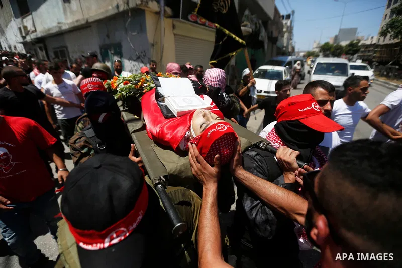 Mourners carry the body of Palestinian teenager Arkan Mezeher, who was killed by Israeli soldiers during a raid, during his funeral in Dheishe refugee camp, near West Bank city of Bethlehem on July 23, 2018. Photo by Wis...