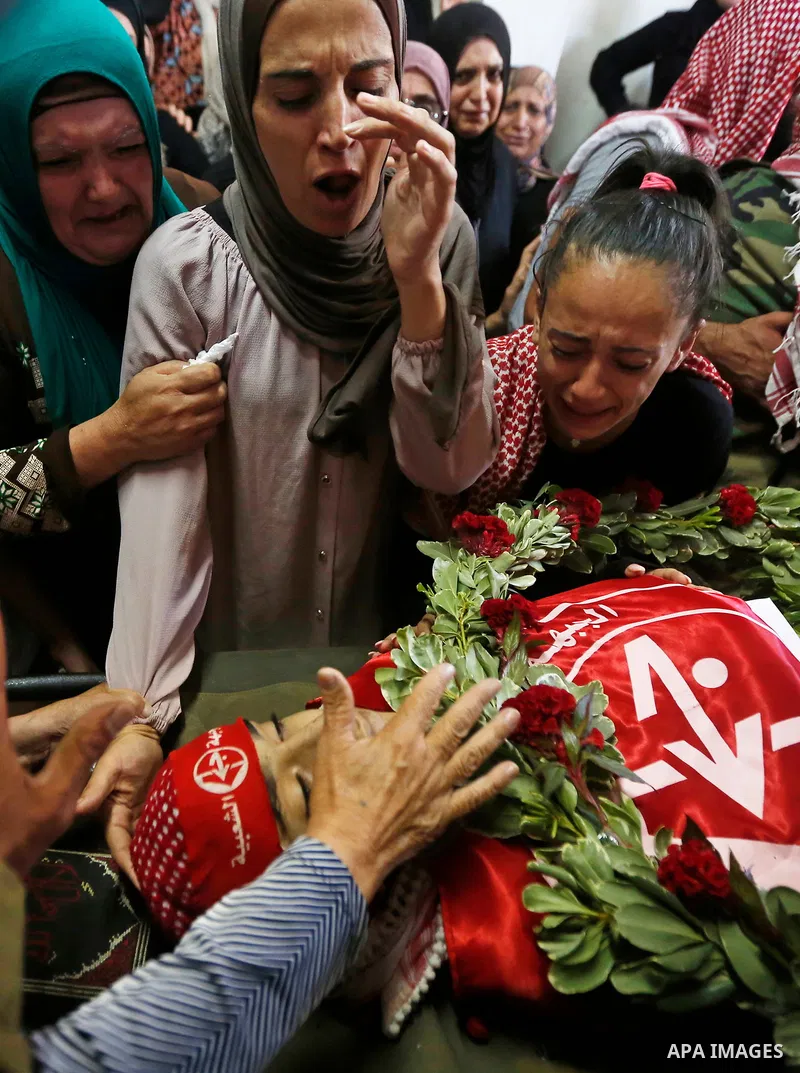 Relatives of Palestinian teenager Arkan Mezeher, who was killed by Israeli soldiers during a raid, mourn over his body during his funeral in Dheishe refugee camp, near West Bank city of Bethlehem on July 23, 2018. Photo...