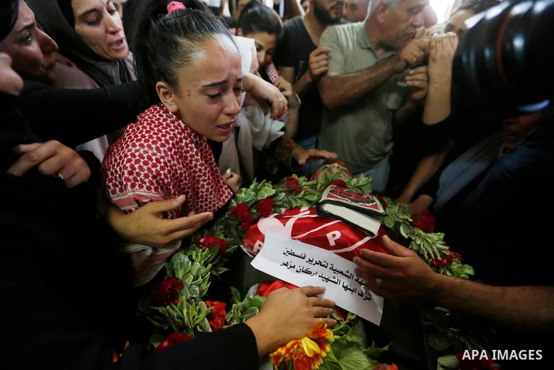 Relatives of Palestinian teenager Arkan Mezeher, who was killed by Israeli soldiers during a raid, mourn over his body during his funeral in Dheishe refugee camp, near West Bank city of Bethlehem on July 23, 2018. Photo...