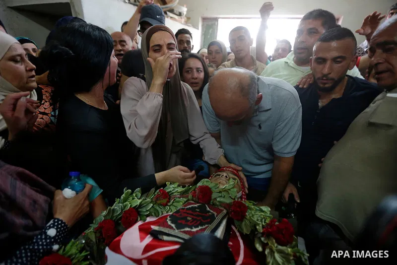 Relatives of Palestinian teenager Arkan Mezeher, who was killed by Israeli soldiers during a raid, mourn over his body during his funeral in Dheishe refugee camp, near West Bank city of Bethlehem on July 23, 2018. Photo...