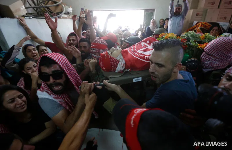 Mourners carry the body of Palestinian teenager Arkan Mezeher, who was killed by Israeli soldiers during a raid, during his funeral in Dheishe refugee camp, near West Bank city of Bethlehem on July 23, 2018. Photo by Wis...