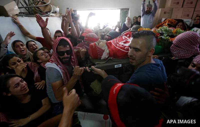 Mourners carry the body of Palestinian teenager Arkan Mezeher, who was killed by Israeli soldiers during a raid, during his funeral in Dheishe refugee camp, near West Bank city of Bethlehem on July 23, 2018. Photo by Wis...
