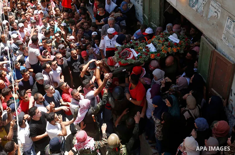 Mourners carry the body of Palestinian teenager Arkan Mezeher, who was killed by Israeli soldiers during a raid, during his funeral in Dheishe refugee camp, near West Bank city of Bethlehem on July 23, 2018. Photo by Wis...