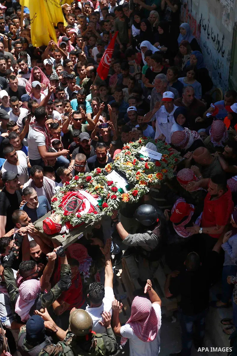 Mourners carry the body of Palestinian teenager Arkan Mezeher, who was killed by Israeli soldiers during a raid, during his funeral in Dheishe refugee camp, near West Bank city of Bethlehem on July 23, 2018. Photo by Wis...