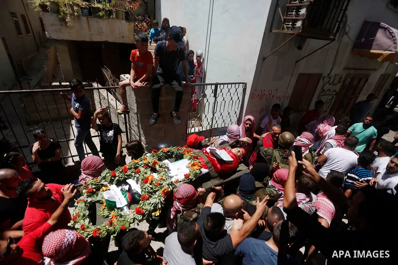 Mourners carry the body of Palestinian teenager Arkan Mezeher, who was killed by Israeli soldiers during a raid, during his funeral in Dheishe refugee camp, near West Bank city of Bethlehem on July 23, 2018. Photo by Wis...