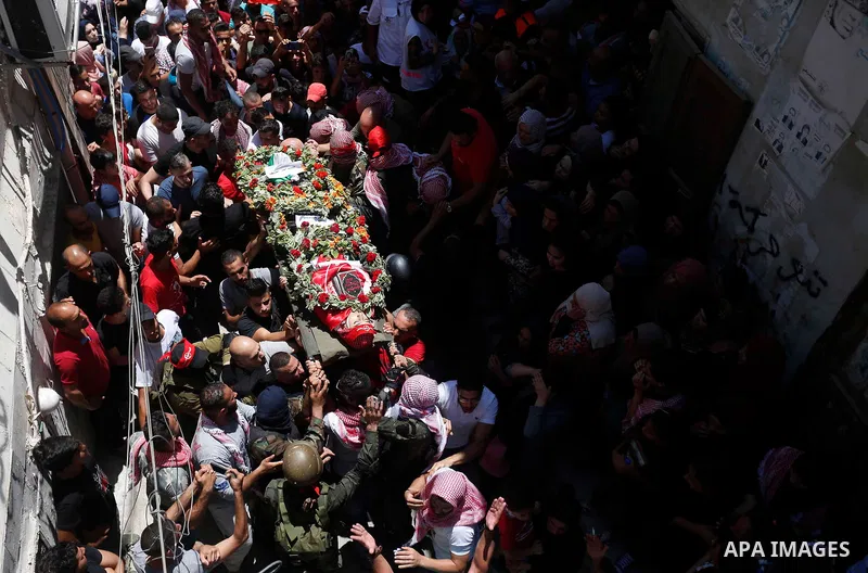 Mourners carry the body of Palestinian teenager Arkan Mezeher, who was killed by Israeli soldiers during a raid, during his funeral in Dheishe refugee camp, near West Bank city of Bethlehem on July 23, 2018. Photo by Wis...