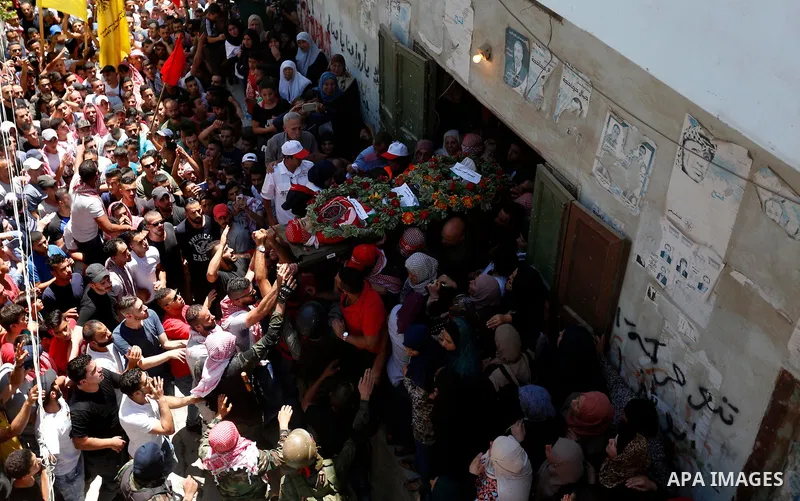 Mourners carry the body of Palestinian teenager Arkan Mezeher, who was killed by Israeli soldiers during a raid, during his funeral in Dheishe refugee camp, near West Bank city of Bethlehem on July 23, 2018. Photo by Wis...