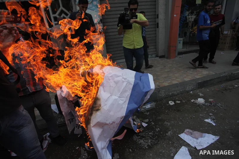 Palestinian supporters of the Islamic Jihad movement burn an Israeli flag and American Flag during a protest to show solidarity with Al-Aqsa mosque, in Gaza city, on July 23, 2018. Photo by Mahmoud Ajour