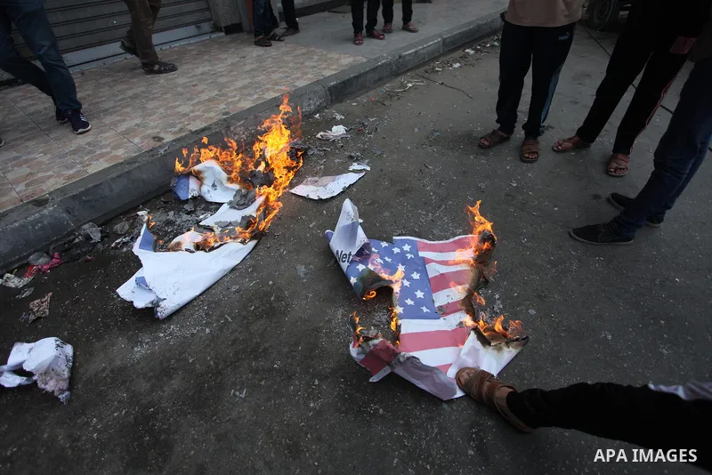 Palestinian supporters of the Islamic Jihad movement burn an Israeli flag and American Flag during a protest to show solidarity with Al-Aqsa mosque, in Gaza city, on July 23, 2018. Photo by Mahmoud Ajour