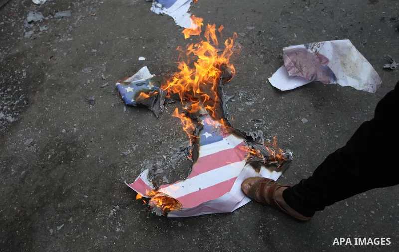 Palestinian supporters of the Islamic Jihad movement burn an Israeli flag and American Flag during a protest to show solidarity with Al-Aqsa mosque, in Gaza city, on July 23, 2018. Photo by Mahmoud Ajour