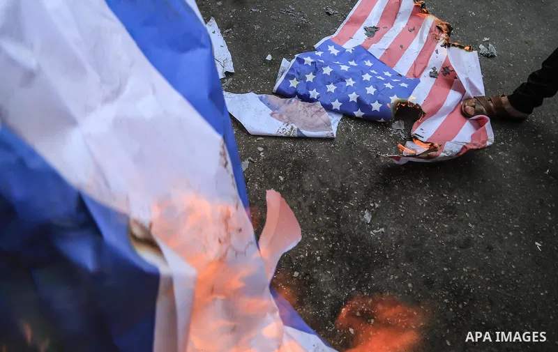 Palestinian supporters of the Islamic Jihad movement burn an Israeli flag and American Flag during a protest to show solidarity with Al-Aqsa mosque, in Gaza city, on July 23, 2018. Photo by Dawoud Abo Alkas