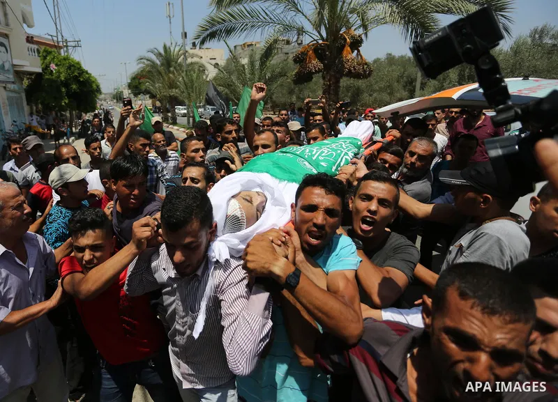 Mourners carry the body of Palestinian Karam Arafat, who died of wounds he sustained during clashes with Israeli troops, during his funeral in Khan Younis in the southern of Gaza strip on July 23, 2018. Photo by Ashraf A...