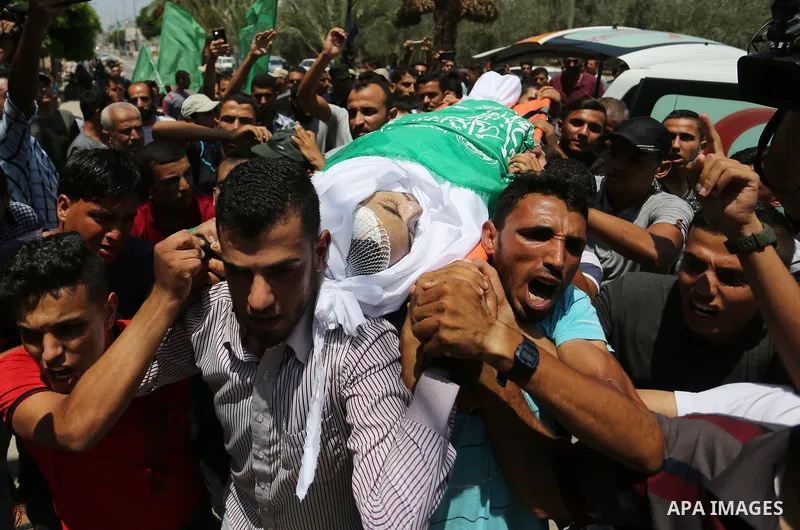 Mourners carry the body of Palestinian Karam Arafat, who died of wounds he sustained during clashes with Israeli troops, during his funeral in Khan Younis in the southern of Gaza strip on July 23, 2018. Photo by Ashraf A...