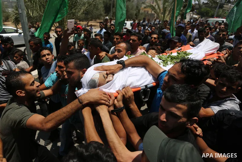 Mourners carry the body of Palestinian Karam Arafat, who died of wounds he sustained during clashes with Israeli troops, during his funeral in Khan Younis in the southern of Gaza strip on July 23, 2018. Photo by Ashraf A...