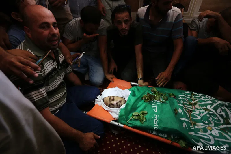 Relatives of Palestinian Karam Arafat,23, who died of wounds he sustained during clashes with Israeli troops, mourn over his body during his funeral in Khan Younis in the southern of Gaza strip on July 23, 2018. Photo by...