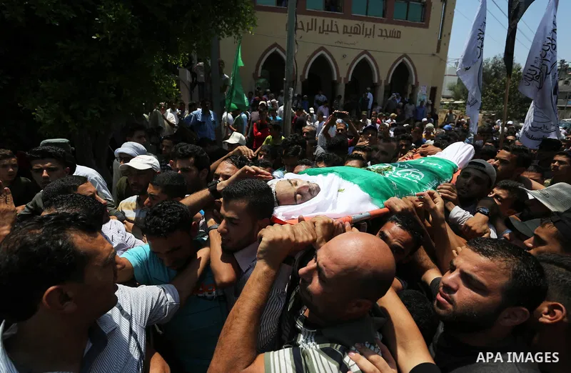 Mourners carry the body of Palestinian Karam Arafat, who died of wounds he sustained during clashes with Israeli troops, during his funeral in Khan Younis in the southern of Gaza strip on July 23, 2018. Photo by Ashraf A...