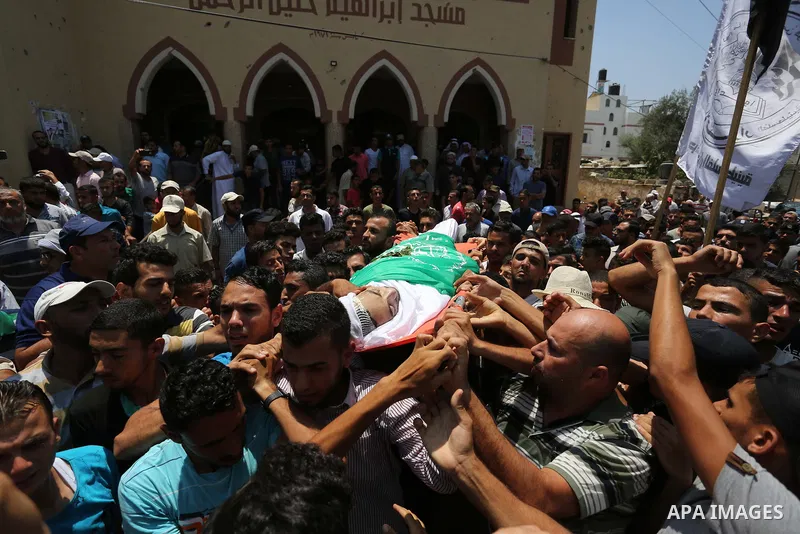 Mourners carry the body of Palestinian Karam Arafat, who died of wounds he sustained during clashes with Israeli troops, during his funeral in Khan Younis in the southern of Gaza strip on July 23, 2018. Photo by Ashraf A...