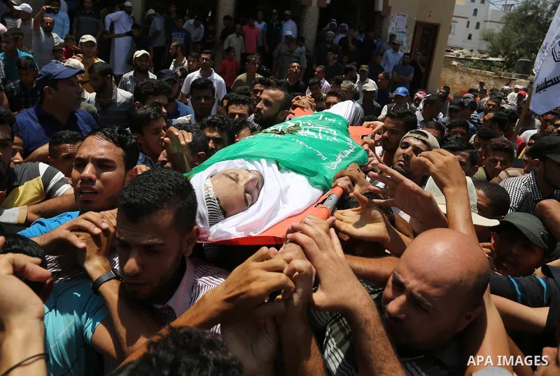 Mourners carry the body of Palestinian Karam Arafat, who died of wounds he sustained during clashes with Israeli troops, during his funeral in Khan Younis in the southern of Gaza strip on July 23, 2018. Photo by Ashraf A...