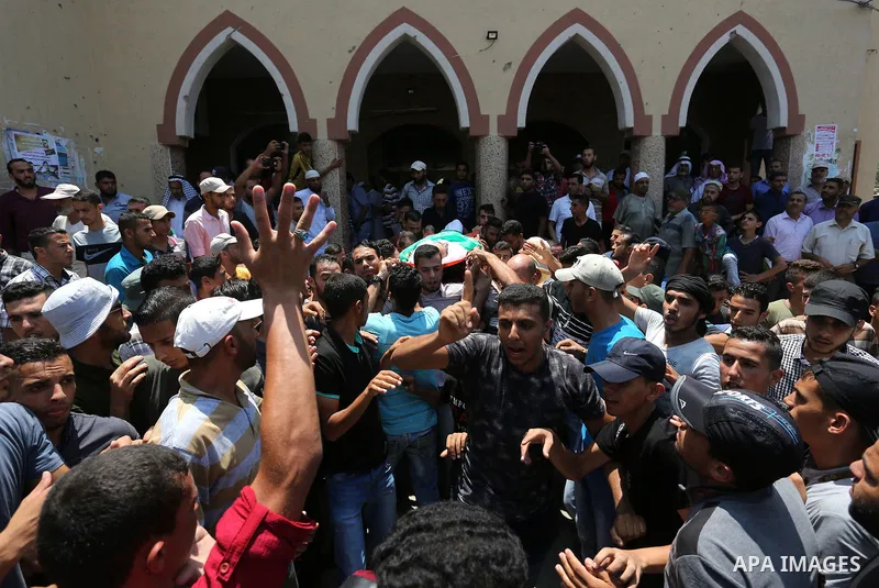Mourners carry the body of Palestinian Karam Arafat, who died of wounds he sustained during clashes with Israeli troops, during his funeral in Khan Younis in the southern of Gaza strip on July 23, 2018. Photo by Ashraf A...