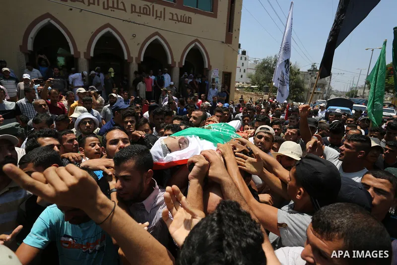 Mourners carry the body of Palestinian Karam Arafat, who died of wounds he sustained during clashes with Israeli troops, during his funeral in Khan Younis in the southern of Gaza strip on July 23, 2018. Photo by Ashraf A...