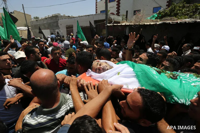 Mourners carry the body of Palestinian Karam Arafat, who died of wounds he sustained during clashes with Israeli troops, during his funeral in Khan Younis in the southern of Gaza strip on July 23, 2018. Photo by Ashraf A...