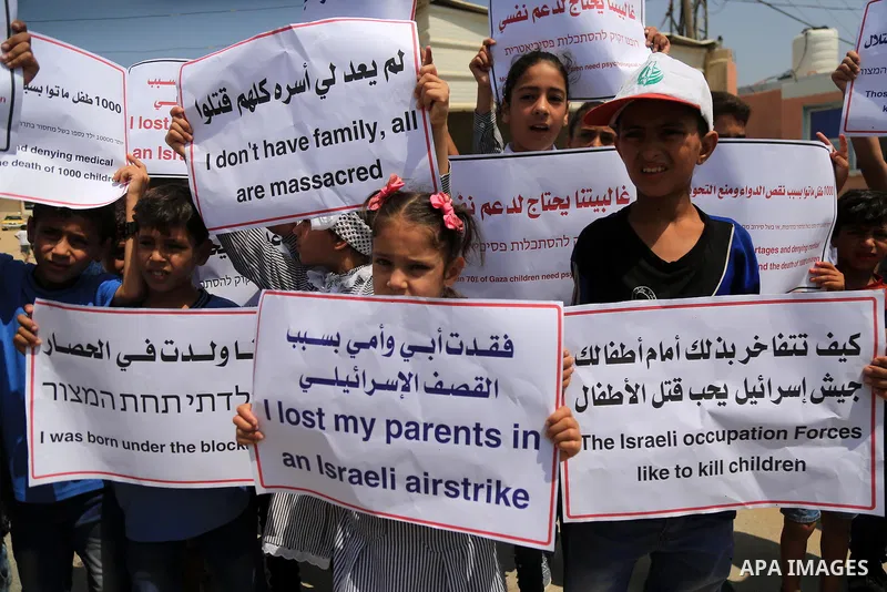 Palestinian children hold banners and candles during in a protest against the continued Israeli siege on the Gaza Strip, at Erez crossing, in the northern Gaza Strip on July 24, 2018. Photo by Dawoud Abo Alkas