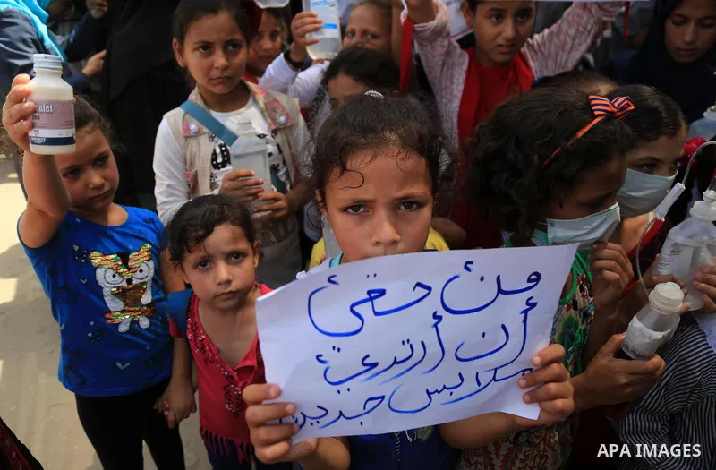 Palestinian children hold banners and candles during in a protest against the continued Israeli siege on the Gaza Strip, at Erez crossing, in the northern Gaza Strip on July 24, 2018. Photo by Dawoud Abo Alkas