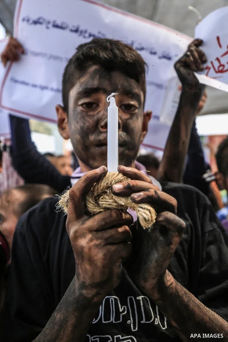 Palestinian children hold banners and candles during in a protest against the continued Israeli siege on the Gaza Strip, at Erez crossing, in the northern Gaza Strip on July 24, 2018. Photo by Dawoud Abo Alkas
